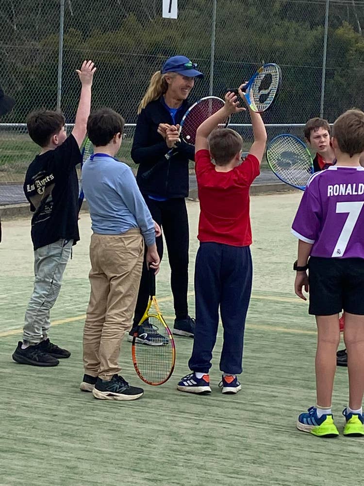 Students with tennis raquets with the tennis coah getting ready to play a game